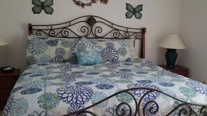 A bedroom with a metal bed frame, floral bedding, a wall decoration, and two butterfly wall art pieces. - Rising Star in Clermont (Clermont)