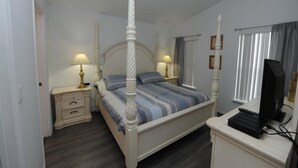 A bedroom with a four-poster bed, bedside tables with lamps, a television on a stand, and a window with curtains. - Dream in Clermont (Clermont)