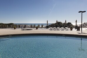 Relax by the pool or on the beach, surrounded by lounge chairs and umbrellas.