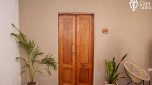 A wooden door with two panels, flanked by potted plants and a woven chair. - Gorgeous Suite w/Premium Ammenties in Downtown (Valladolid)