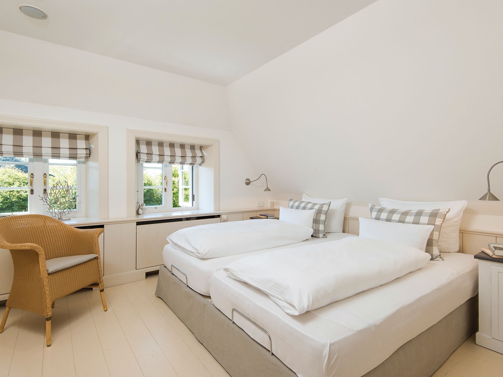 Ein Schlafzimmer mit zwei Betten, einem Schreibtisch, einem Stuhl und einem Fenster mit Vorhängen.