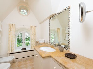 A bathroom with a large mirror, a sink, a bidet, and a window with star-patterned curtains. - Biike Hüs from A&M - Biike Hüs (Kampen (Sylt))