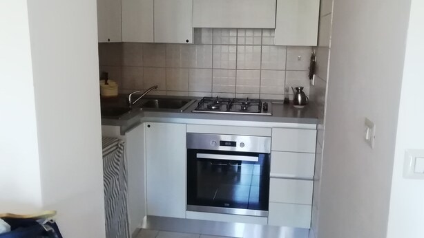 Een kleine keuken met witte kasten, een roestvrijstalen fornuis en een oven.