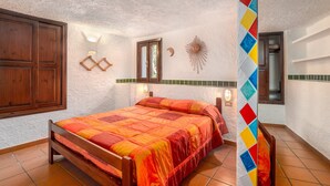 A bedroom with a wooden bed, a window, a wall-mounted decorative item, and a door. - Tranquil Apartment "Leccio" on the Beach with Terrace, Garden & Wi-Fi (San Teodoro)