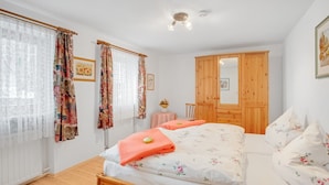 A bedroom with a bed, a wooden wardrobe, a small table with a vase, and a chair. - Apartment "König" with Terrace, Wi-Fi, Garden & Mountain View (Berchtesgaden)