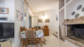 Una sala de estar con chimenea, una mesa de comedor, sillas y un televisor.