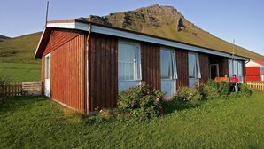 Un bâtiment en bois avec un toit en pente, de grandes fenêtres et une personne se tenant près de l’entrée.