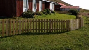 Un bâtiment rouge avec de grandes fenêtres, une clôture en bois et une pelouse devant.