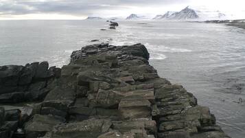 A rocky shoreline with a view of the sea and distant mountains.