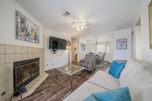 A living room with a fireplace, a sofa, a coffee table, and a dining area with a chandelier.