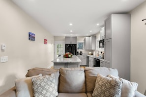 Relax in this inviting living space with a comfortable sofa and adjacent kitchen area featuring modern appliances.