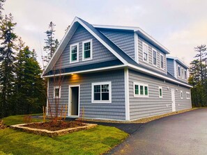 Stunning two-story home with a modern design, featuring a front entrance, porch, and beautifully manicured lawn.