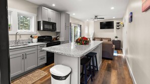 A modern kitchen with granite countertops, stainless steel appliances, and a central island with stools. - The Overlook at Orchard Hills -- Hilltop Retreat,  Near Acadia (Tremont)