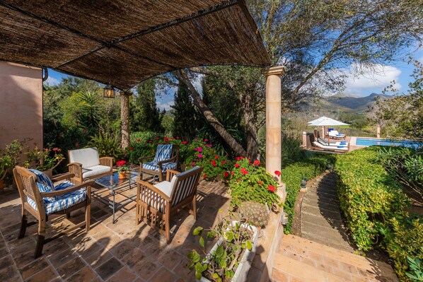 An outdoor patio with wooden furniture, a pool, and a view of mountains.