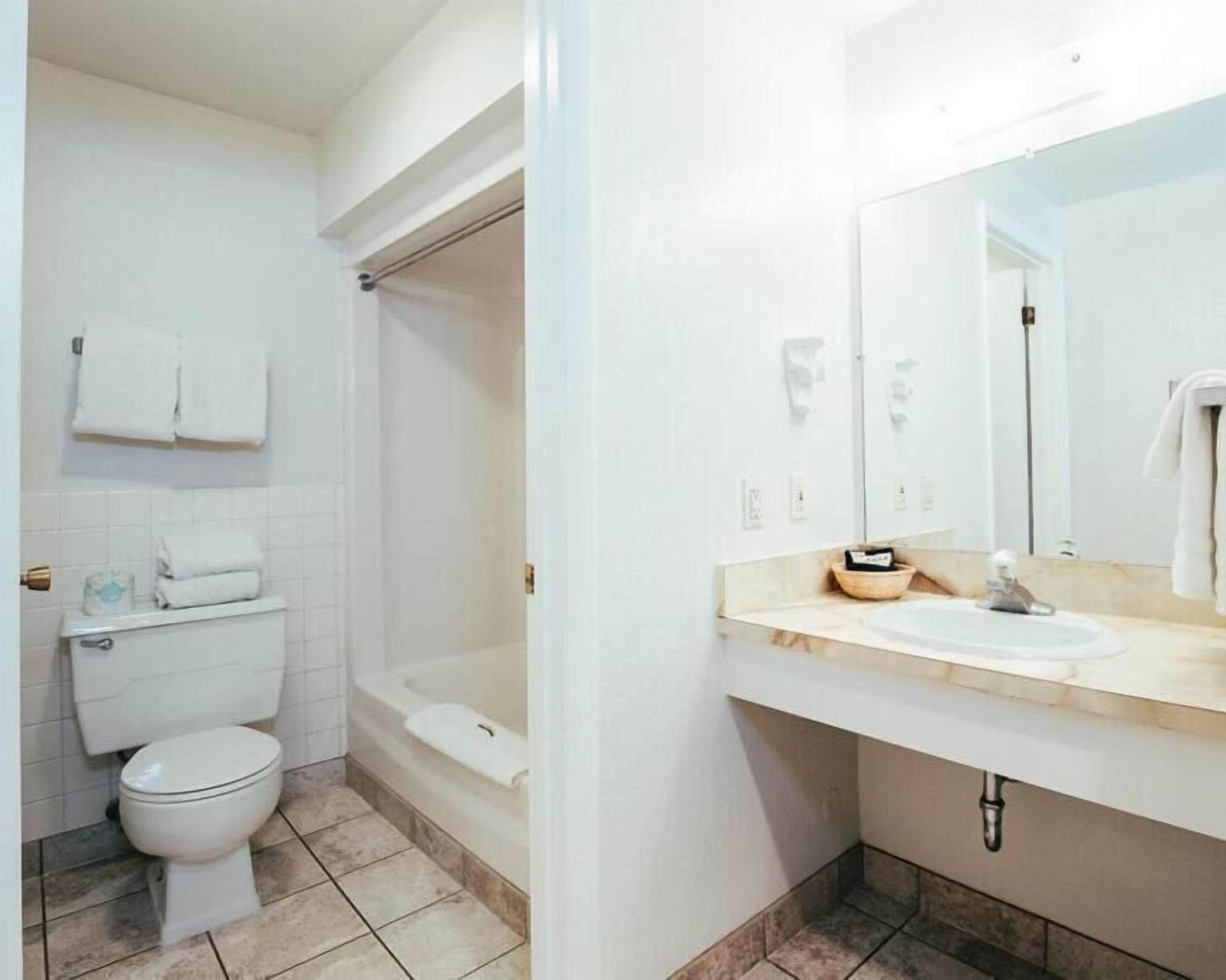 Un baño con inodoro, bañera, lavabo y espejo.