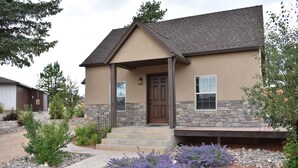 A two-story house with a stone facade, a front porch, and a well-maintained garden with purple flowers. - Bryce Canyon Pines (Bryce Canyon)