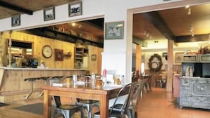 A dining area with a wooden table and chairs, a bar area with shelves and a clock, and a kitchen area with a sink and cabinets. - Bryce Canyon Pines (Bryce Canyon)