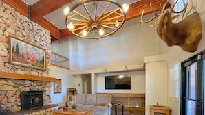 A cozy living room with a stone fireplace, a large sofa, a coffee table, and a mounted deer head. - Bryce Canyon Pines (Bryce Canyon)
