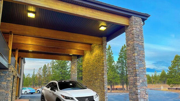 A white SUV parked under a covered area with stone pillars and a wooden roof. - Bryce Canyon Pines (Bryce Canyon)