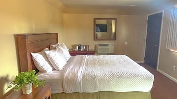 Una habitación de hotel con cama, mesita de noche y espejo.
