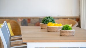 Een eettafel met rieten manden vol citroenen en een klein plantje, in een kamer met een houten vloer en een witte muur.