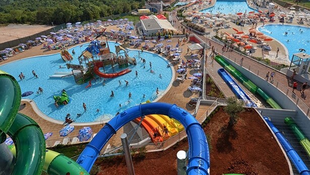 Un parque acuático con múltiples piscinas, toboganes y una zona de juegos amplia.
