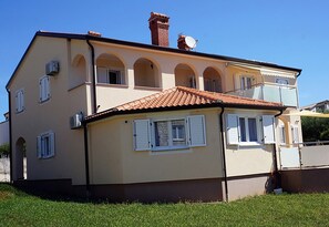 A two-story house with a tiled roof, multiple windows with shutters, and a satellite dish. - Willa Trojka (Novigrad)