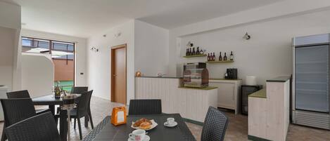 Una cocina moderna con comedor, que incluye una mesa con sillas, un refrigerador y una encimera con botellas.