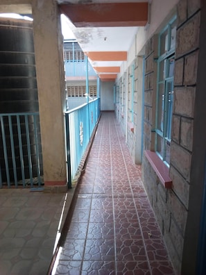 A corridor with tiled flooring, blue railings, and brick walls. - Boabab Guest House (Wote)