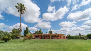 Un grand bâtiment d’un seul étage, doté d’un toit recouvert de tuiles rouges, entouré d’une pelouse bien entretenue et de divers arbres.