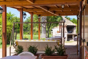 Un espacio de estar al aire libre cubierto, con vistas a un edificio de piedra y una parrilla.