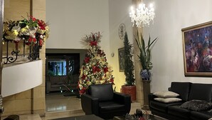 Een ruime woonkamer met een grote kerstboom, zwarte leren banken, een bijzettafeltje en een kroonluchter.