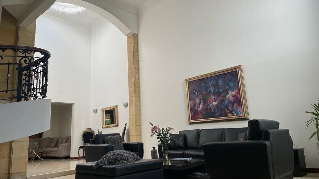 Un salón amplio con un sofá de cuero negro, una mesa de centro y un cuadro en la pared.