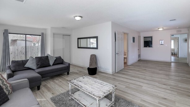 A spacious living room with a grey sectional sofa, a white coffee table, and a large window with curtains. - Spacious West Side Home away from Home! (Wichita)