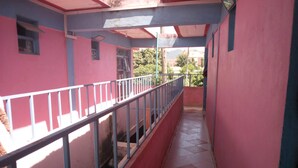 A narrow corridor with a metal railing, tiled floor, and pink walls. - Eden Garden Hotel (Wote)