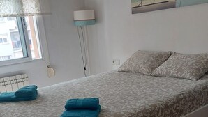 Una camera da letto con un letto, una finestra, un quadro e una lampada.
