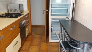 Una cucina compatta con mobili in legno, piano cottura a gas, forno a microonde e frigorifero integrato.