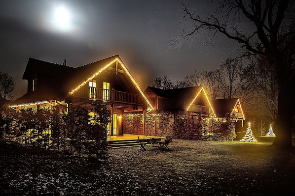 Ein Haus mit Veranda, einer Bank und Weihnachtsbeleuchtung.