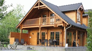 A wooden cabin with a balcony, outdoor seating, and a covered patio area. - Luxury Wooden Villa Albert in Forested Area with Stunning Countryside Views (Den Ham)