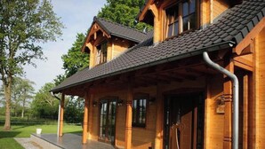A wooden house with a covered porch, large windows, and a door with a metal handle. - Luxury Wooden Villa Albert in Forested Area with Stunning Countryside Views (Den Ham)