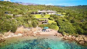 Une propriété située sur la côte, comprenant une grande maison, une piscine et un espace de plage.