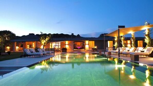 Une maison moderne dotée d’une piscine, d’un espace extérieur aménagé et d’un intérieur bien éclairé.