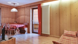 Un intérieur en bois comprenant une table à manger, des chaises, un canapé et un téléviseur posé sur un meuble en bois.