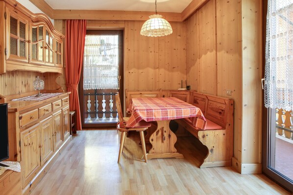 A wooden interior with a dining table, cabinets, and a large window.