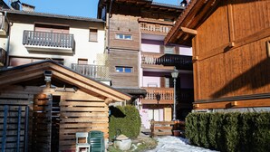 Une rue étroite bordée de bâtiments en bois, de balcons et dont le sol est recouvert de neige.
