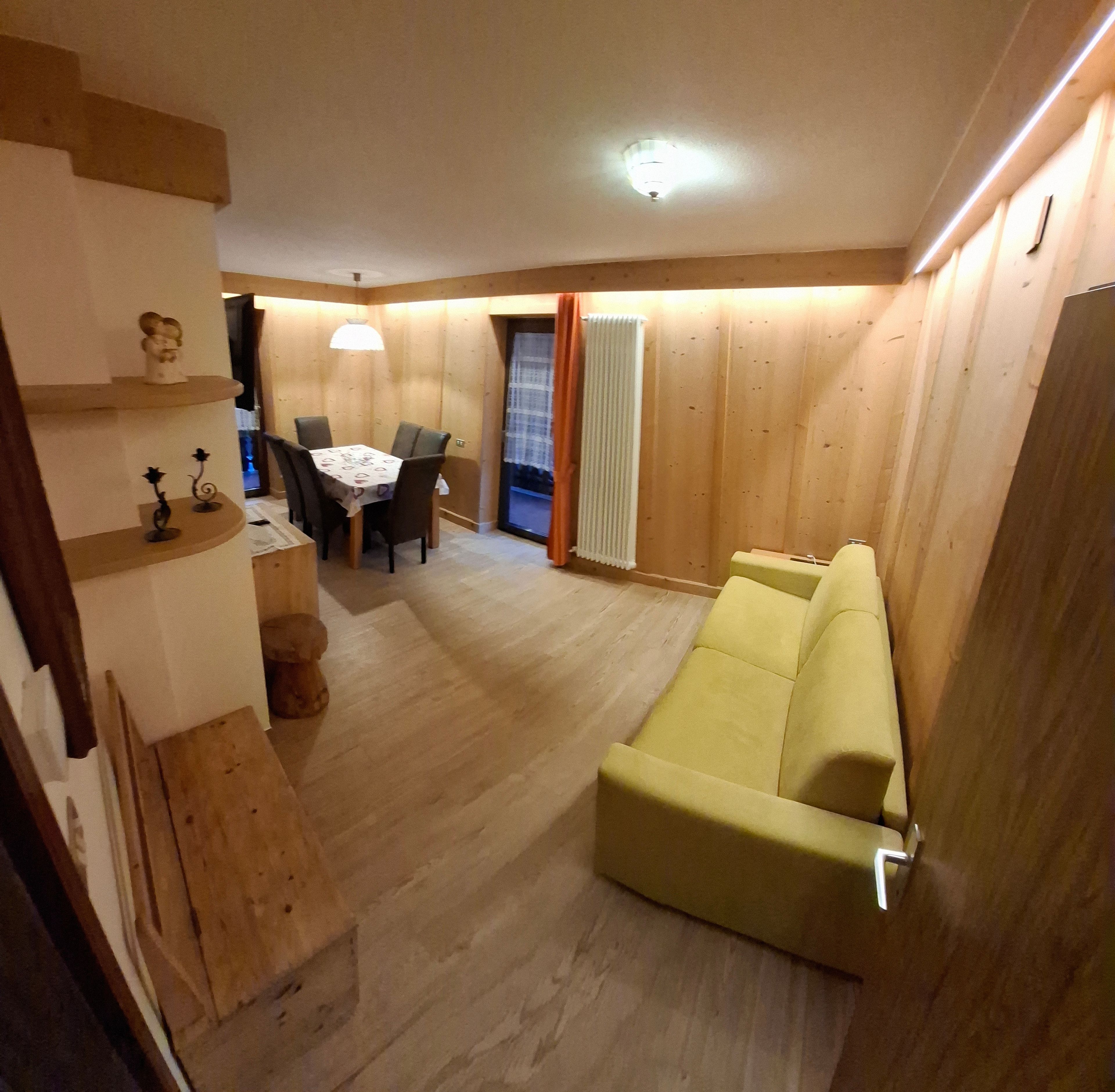 Ein Zimmer mit einem gelben Sofa, einem Esstisch mit Stühlen und einer Treppe.