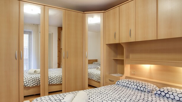 Une chambre à coucher avec un grand lit, une armoire aux portes miroir et une table de chevet.