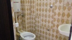 Een badkamer met toilet en wastafel, beide in het wit. De muren hebben een ruitmotief in beige en bruin.