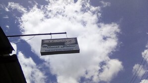 Een bordje voor een gastenverblijf, met een heldere lucht op de achtergrond.