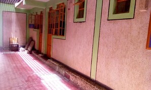 A hallway with a tiled floor, wooden doors, and a bench. - Evening Dew Guest Palour (Nairobi)